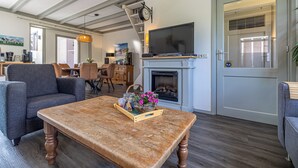 Ein Wohnzimmer mit Kamin, Fernseher und Essbereich mit Stühlen und Tisch.