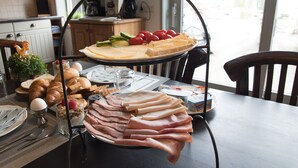 En frukostbuffé med ett varierat utbud av mat, inklusive bröd, ost, skinka och grönsaker.