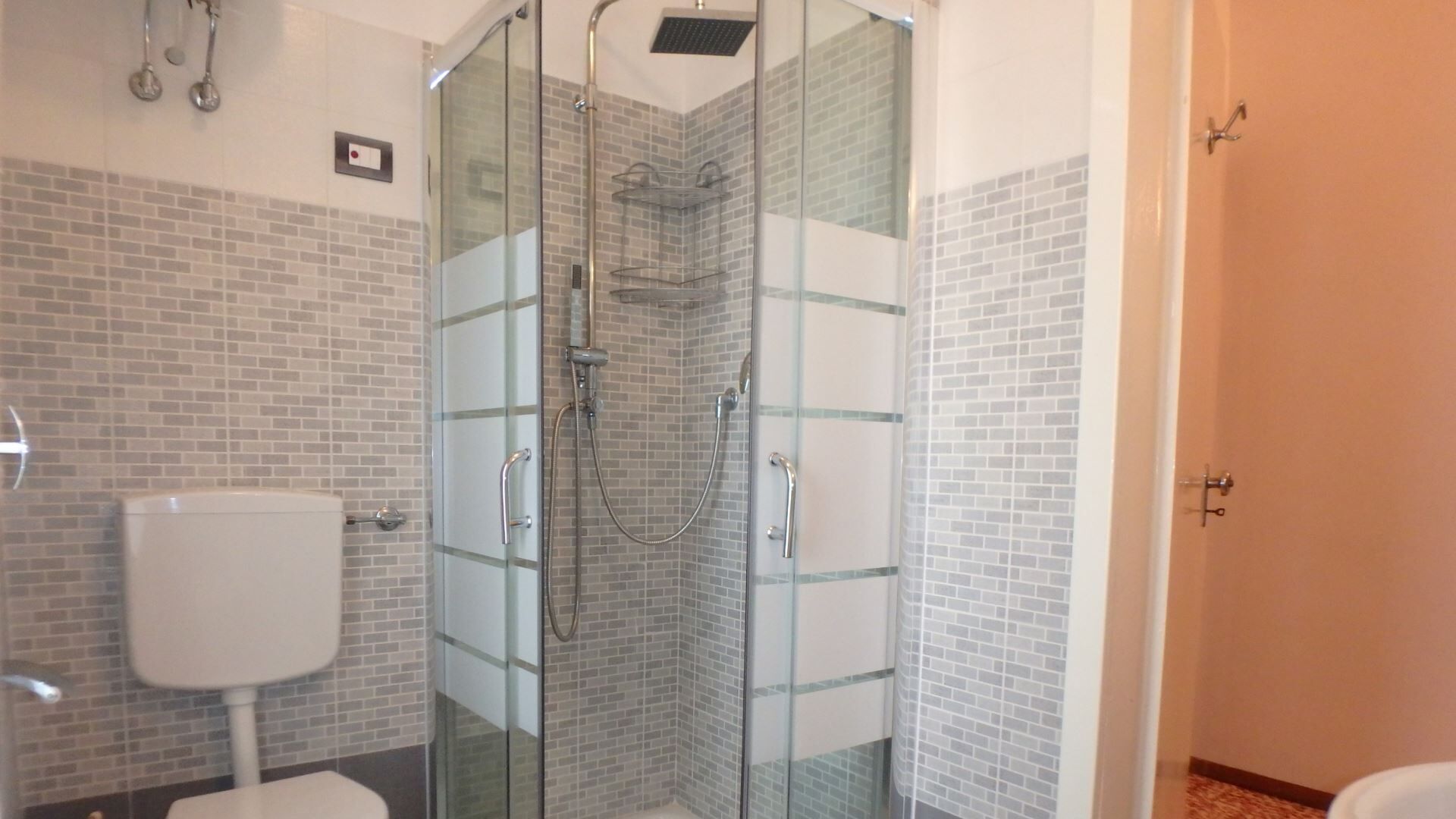 A bathroom with a glass-enclosed shower, a toilet, and a sink.