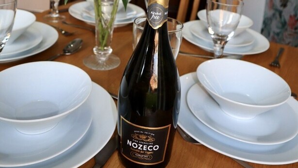 A dining table set with white plates, a bottle of Nozeco champagne, and a vase of pink lilies. - In Our Liverpool Home, 3 Bedrooms Sleeps 5 (Liverpool)