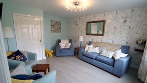A living room with a blue sofa, a yellow chair, a wooden coffee table, and a lamp. - In Our Liverpool Home, 3 Bedrooms Sleeps 5 (Liverpool)