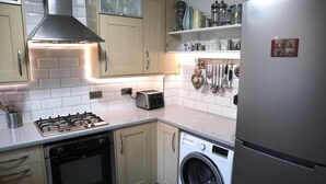 A modern kitchen with a gas stove, oven, washing machine, and a refrigerator. - In Our Liverpool Home, 3 Bedrooms Sleeps 5 (Liverpool)