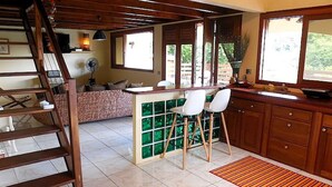 Een ruime keuken met een centraal eiland, houten kastjes en een betegelde vloer.