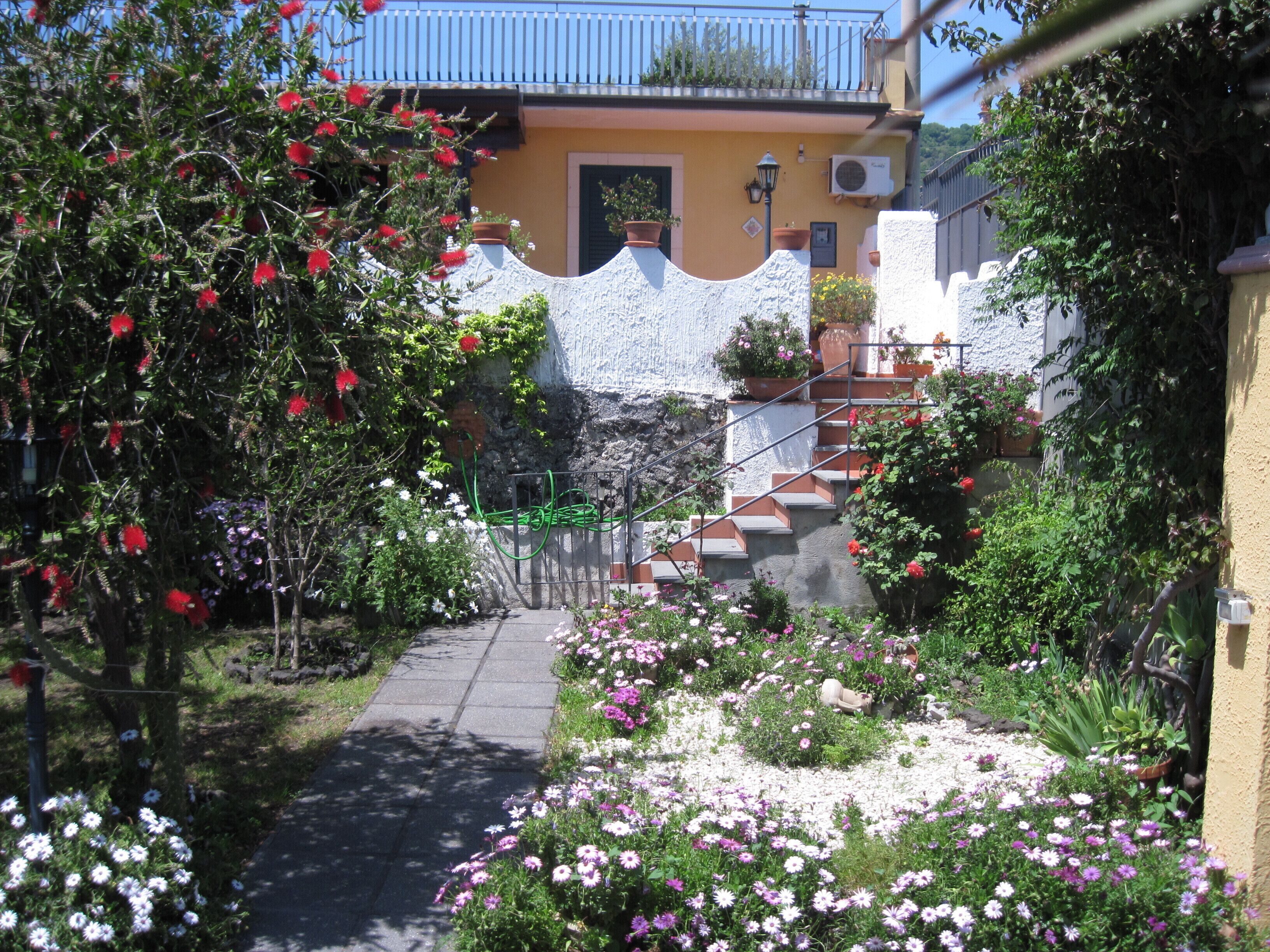 A garden pathway leading to a house with a stone wall and a staircase.
