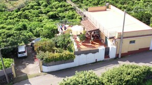 Un edificio con techo plano, balcón y zona pavimentada con plantas en macetas.