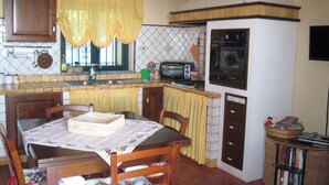 Una cocina compacta con una mesa, sillas, microondas y un refrigerador pequeño.