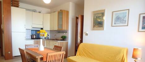 A compact living space with a dining area, kitchenette, and a sofa.