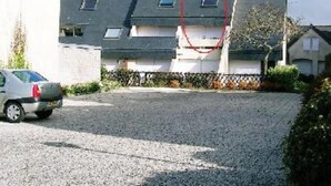 Un edificio residencial con entrada de grava y un coche estacionado.