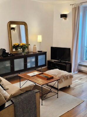 A modern living room with a sofa, a coffee table, a TV, and a cabinet with a mirror.