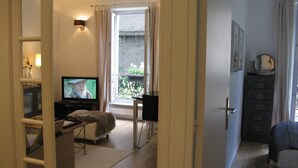 A living room with a television, a sofa, a small table, and a window with curtains. - Apartment/ flat - Paris (Paris)