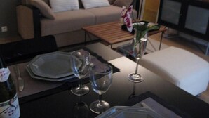 A living room with a sofa, a coffee table, a TV, and a dining area with a table set for two. - Apartment/ flat - Paris (Paris)