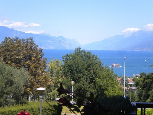 A coastal view with a boat on the water, mountains in the background, and greenery in the foreground.