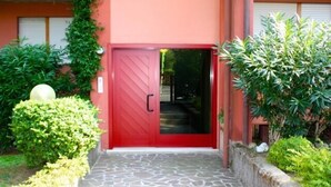 A red door with a glass panel, leading to a stone-paved entrance.