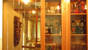 A room with a wooden cabinet containing various bottles and a glass display case with more bottles.