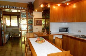 A compact kitchen with wooden cabinets, a microwave, and a dining area with a fruit bowl.