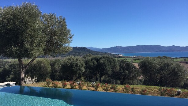 Una piscina azul cristalina con vistas a un paisaje montañoso y una masa de agua al fondo.