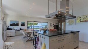 Una cocina moderna con una isla grande, armarios blancos y vistas al exterior.