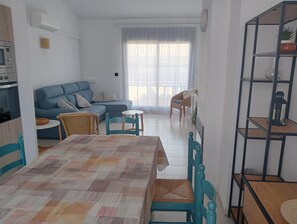 A living room with a sofa, a dining table, and chairs. There is a kitchen area with an oven and a microwave. - Penthouse in l'Escala with communal pool. (L'Escala)