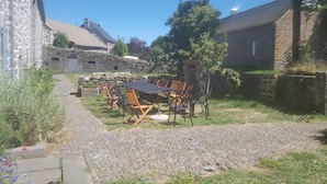 A stone building with a cobblestone path leading to a patio with a table and chairs. - GRAND FERME AVEC PISCINE INTERIEURE ET SALLE DES JEUX (Virargues)