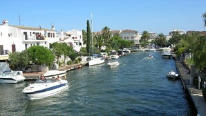 A canal with boats, waterfront buildings, and palm trees. - Newly renovated apartment on the canals (Empuriabrava)