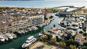 A marina with multiple boats docked, surrounded by residential buildings with balconies and a beach in the background. - Newly renovated apartment on the canals (Empuriabrava)