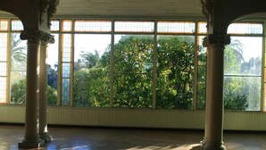A spacious room with large windows, wooden flooring, and classical columns.