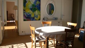 A dining area with a round table, chairs, a painting, a mirror, and a cabinet.