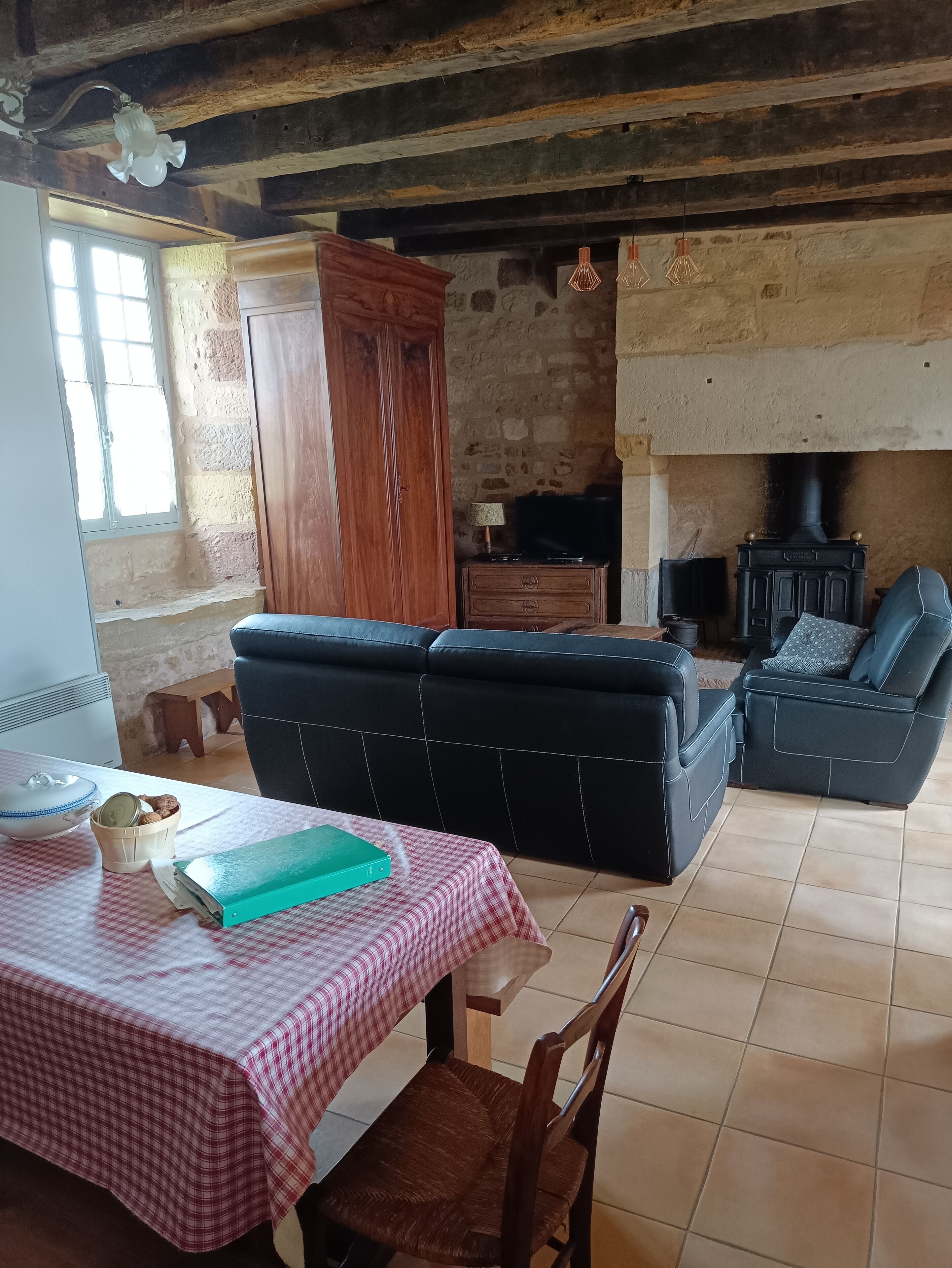 Ein gemütliches Wohnzimmer mit Kamin, einer Couch, einem Esstisch mit kariertem Tischläufer und einem Fernseher.
