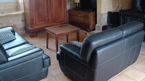 Een rustieke woonkamer met een stenen muur, houten meubels en een open haard.