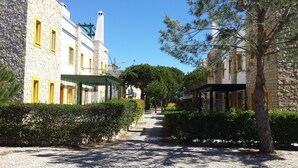 A cobblestone street lined with stone buildings, some with yellow window frames, and a covered walkway on the right. - Cozy Villa, Praia Verde, Algarve (Praia Verde)