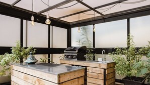 Cozinha moderna com armários de madeira, churrasqueira embutida e plantas em vasos.
