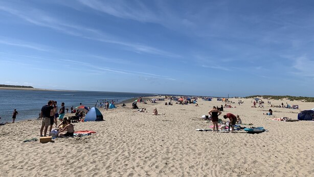 Une vaste plage de sable où l’on voit des tentes et des gens.
