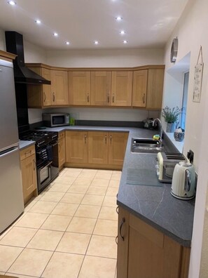 Kitchen features a microwave, kettle, and toaster on the countertop, with a tiled floor and ceiling lights.