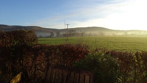 A rural landscape with rolling hills, a clear sky, and a wooden fence in the foreground. - Welcome to Tuolumne Cottage (Denbigh)