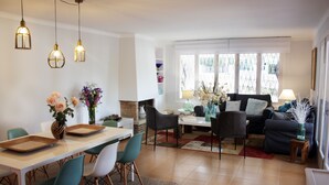 Ein modernes Wohnzimmer mit Essbereich, ausgestattet mit Kamin, einer Sofagarnitur und einem Esstisch mit Stühlen.