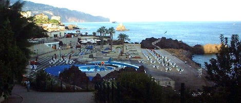 Una località balneare con piscina, lettini e ombrelloni.