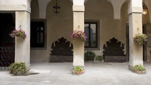 A building with three arches, each with a hanging light fixture and a planter with flowers. - Elegant, confortable flat in historical house, in the heart of Città Alta (Bergamo)