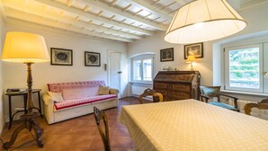 A cozy room with a sofa, a wooden chest, a dining table, and a lamp. - Elegant, confortable flat in historical house, in the heart of Città Alta (Bergamo)
