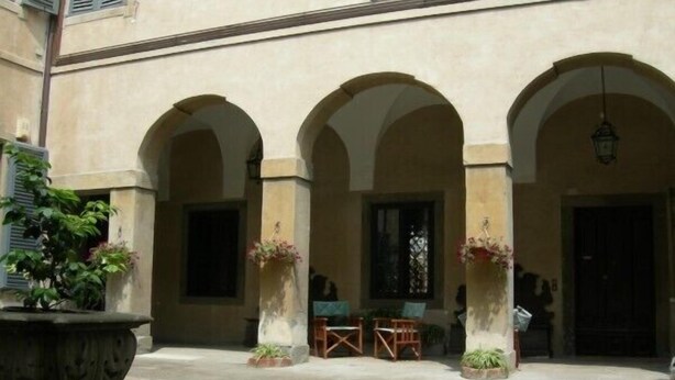 A courtyard with three arches, a table, and chairs. - Elegant, confortable flat in historical house, in the heart of Città Alta (Bergamo)
