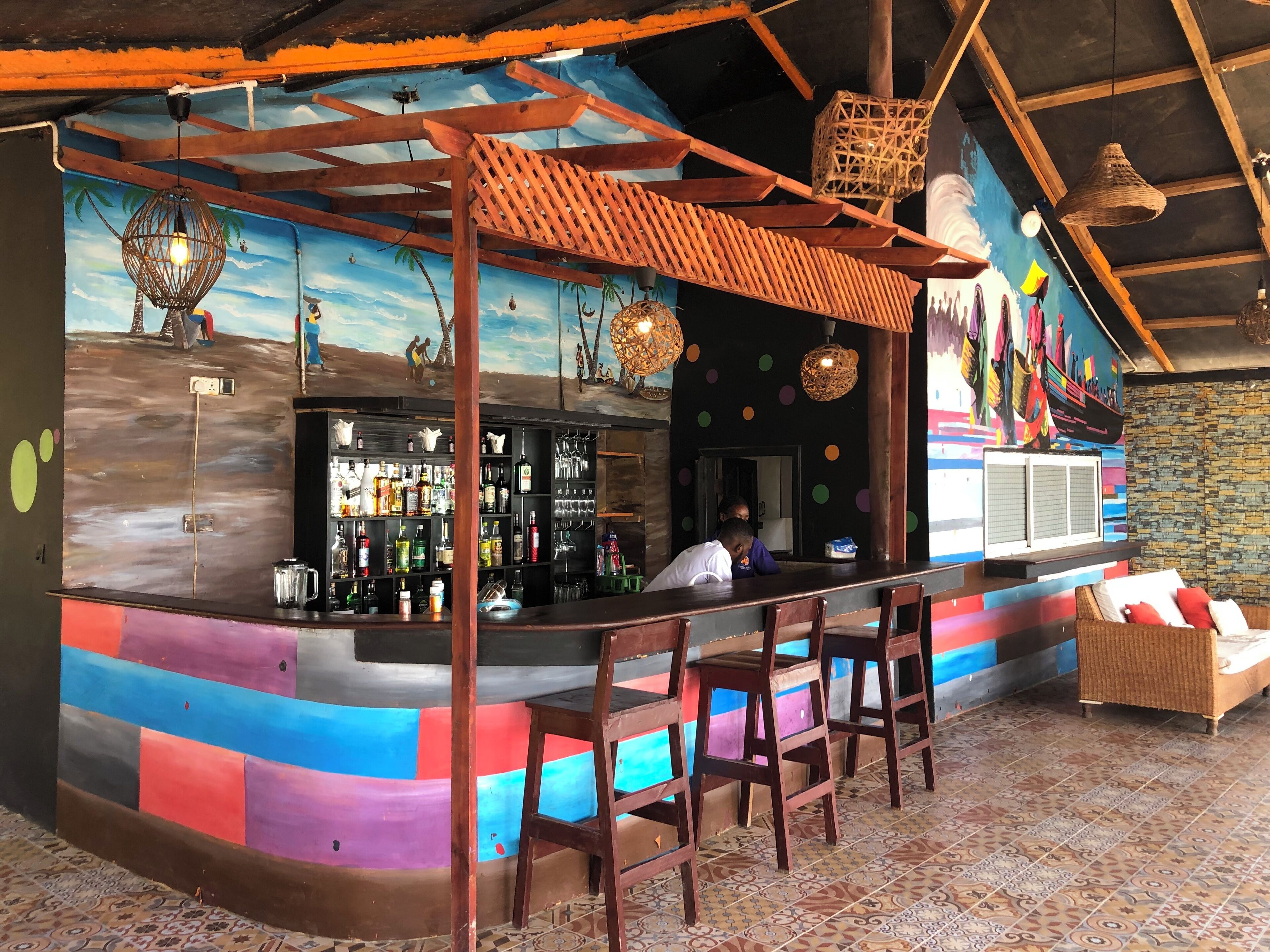 A bar area with a colorful mural, wooden bar counter, and seating.