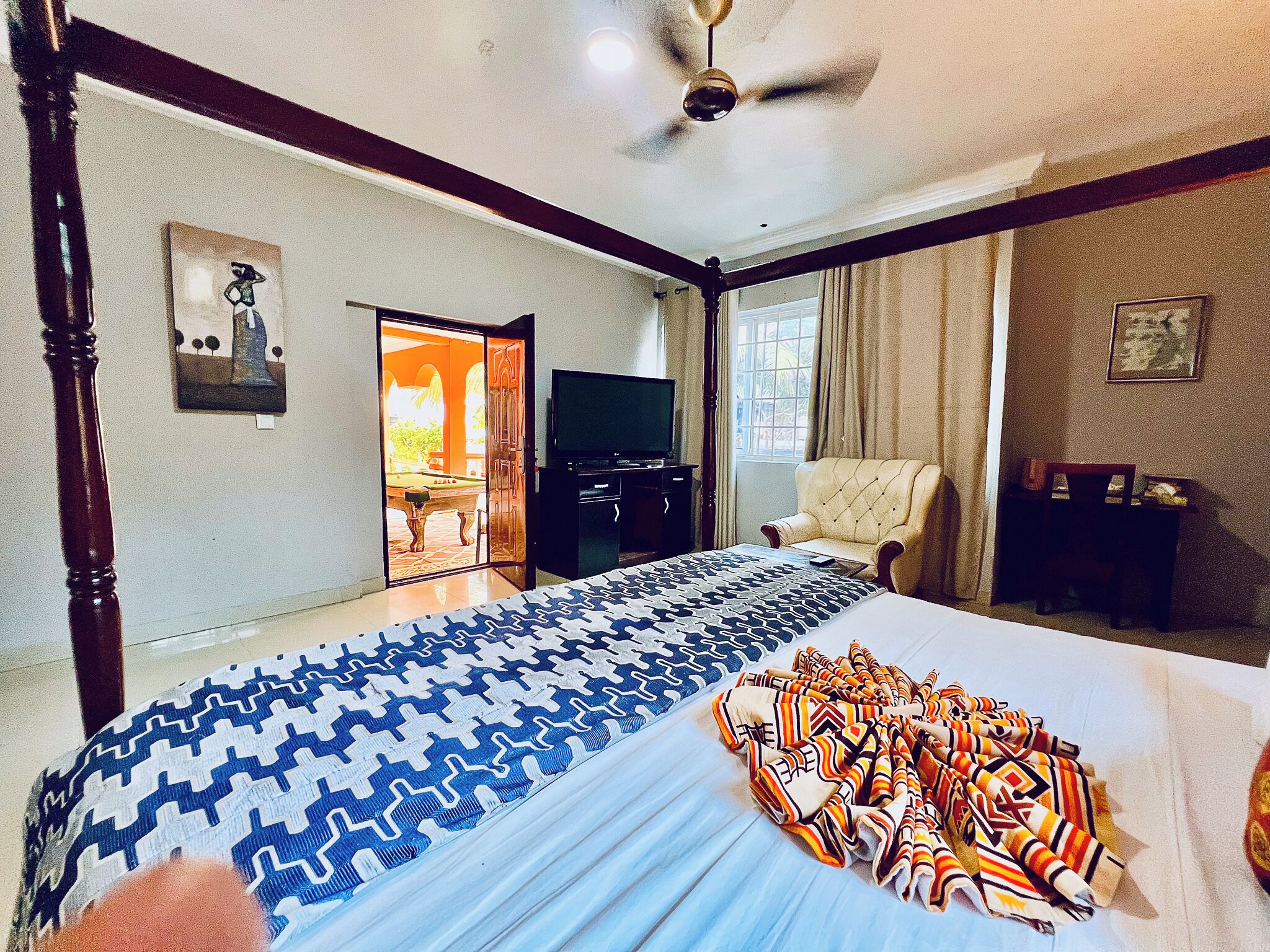 A hotel room with a large bed, a television, a desk, and a chair.