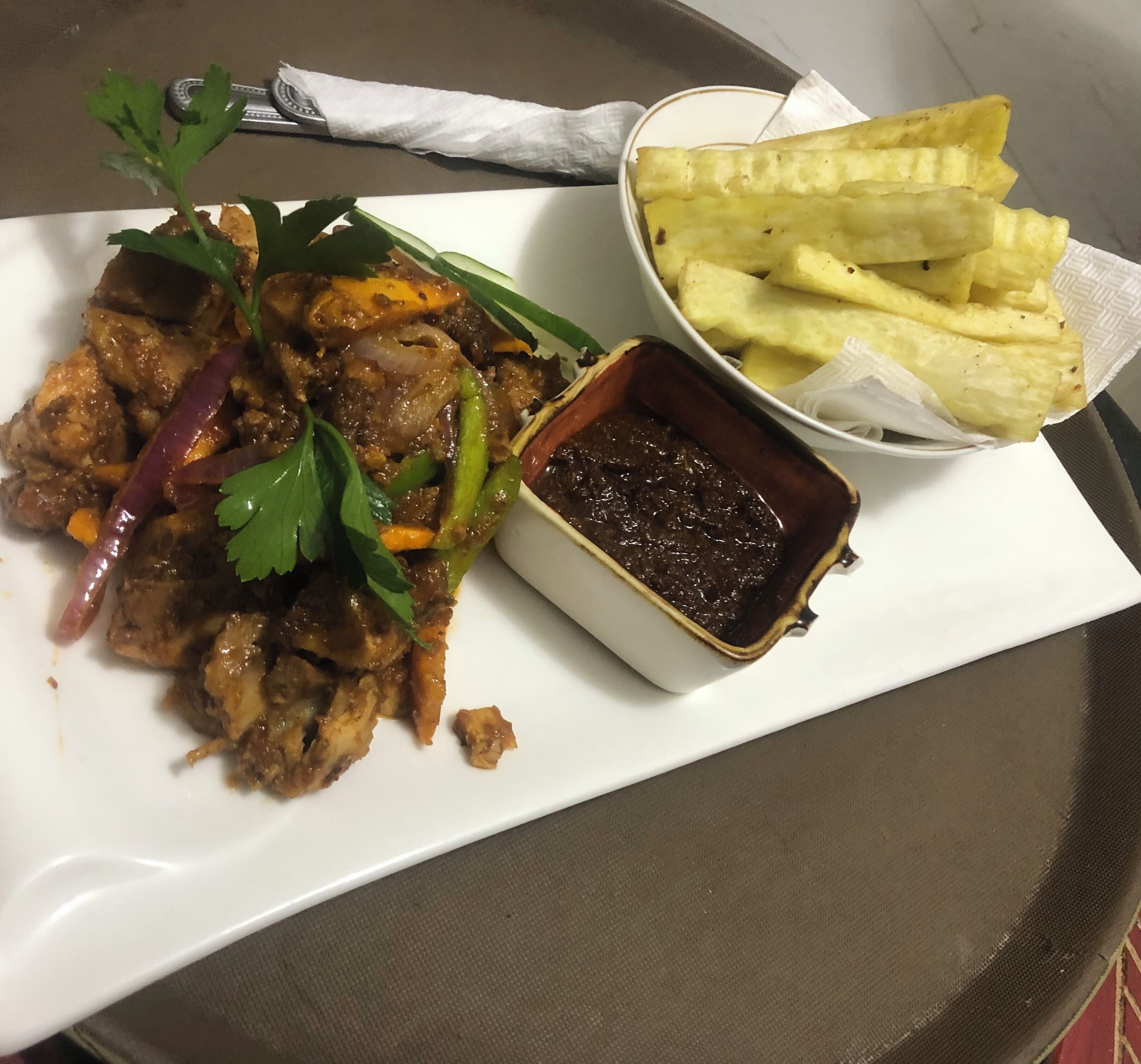 A plate of meat with vegetables and a side of fries and sauce.