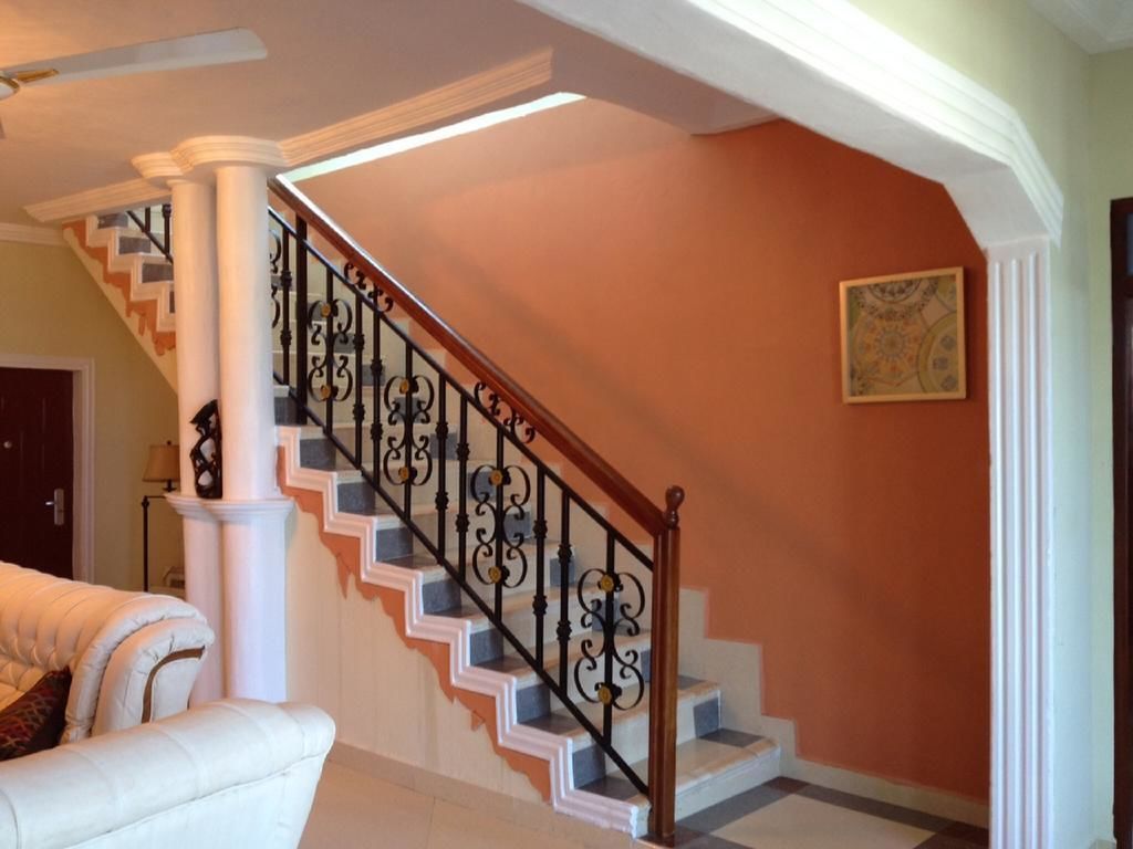 A staircase with ornate black balusters and white steps, leading to a landing with a framed artwork.