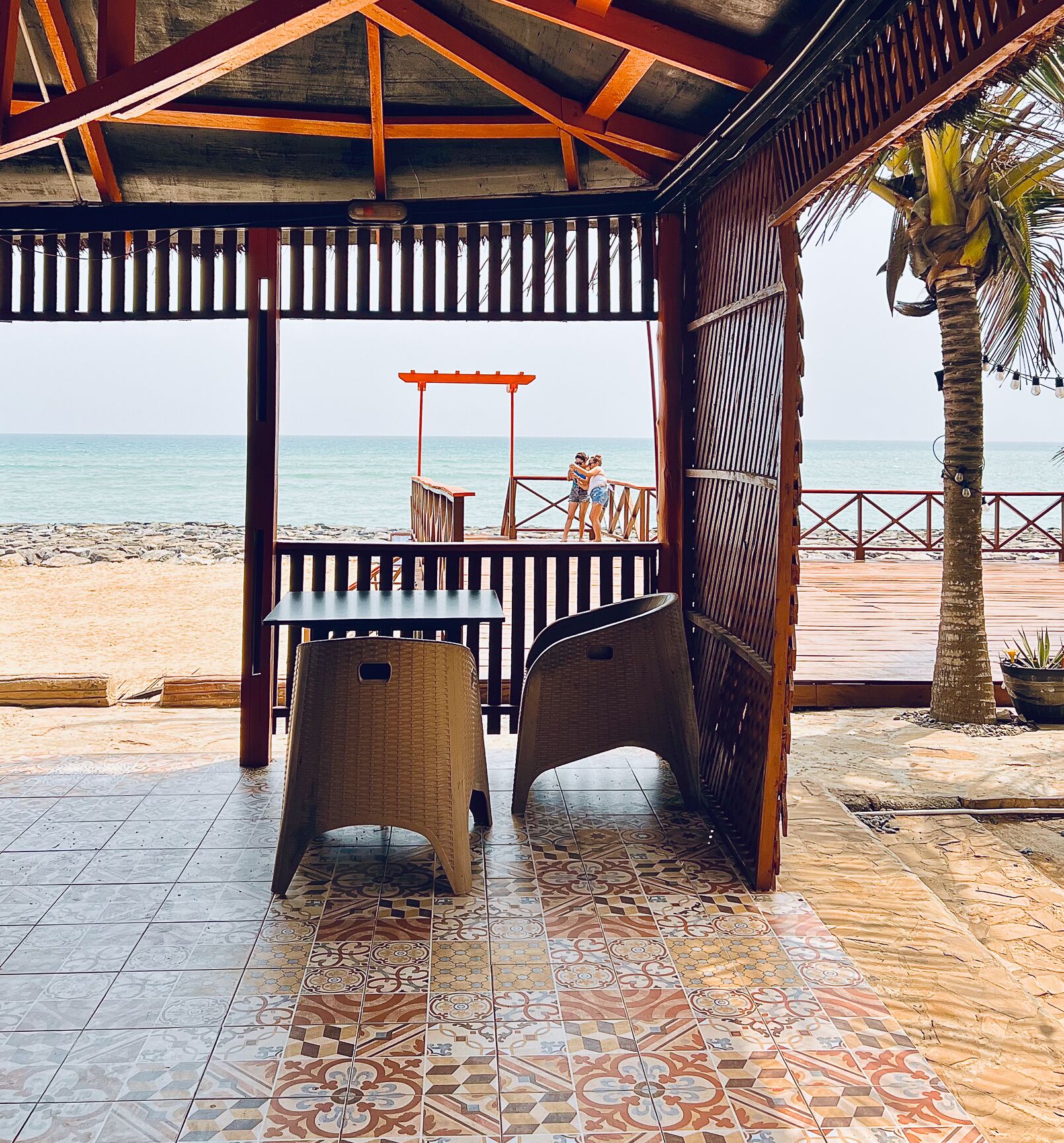 A covered outdoor seating area with a view of the beach and ocean.