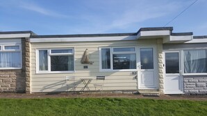 A two-story mobile home with a small porch, a sailboat decoration, and a 'Seaside Cottage' sign.
