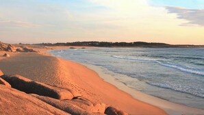 Una playa con rocas grandes y un mar tranquilo.