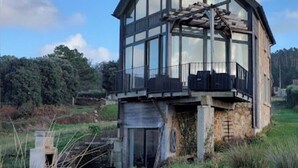 Una casa moderna de dos pisos con ventanas amplias, un balcón y cimientos de piedra.