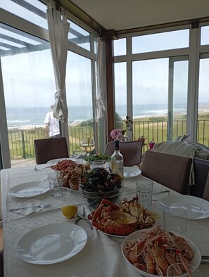 Una mesa de comedor con platos de mariscos, una botella de vino y vistas al océano.