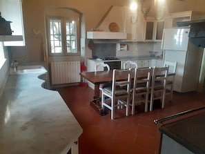 A kitchen with a dining table, chairs, a stove, cabinets, and a window.