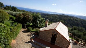 A stone building with a sloped roof, surrounded by lush greenery and a view of the sea. - Villa With Fantastic Sea Views, Surrounded By Vineyards CITRA  009022-LT-0083 (Celle Ligure)
